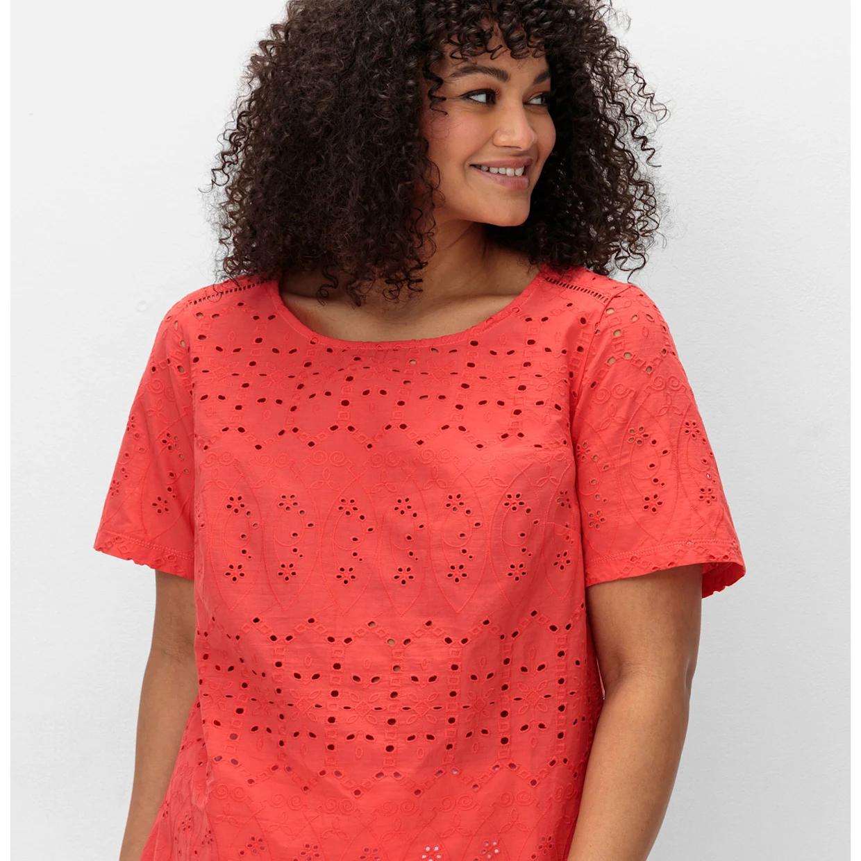 Model mit korallefarbenem Shirt mit Lochstickereien Model mit korallefarbenem Shirt mit Lochstickereien