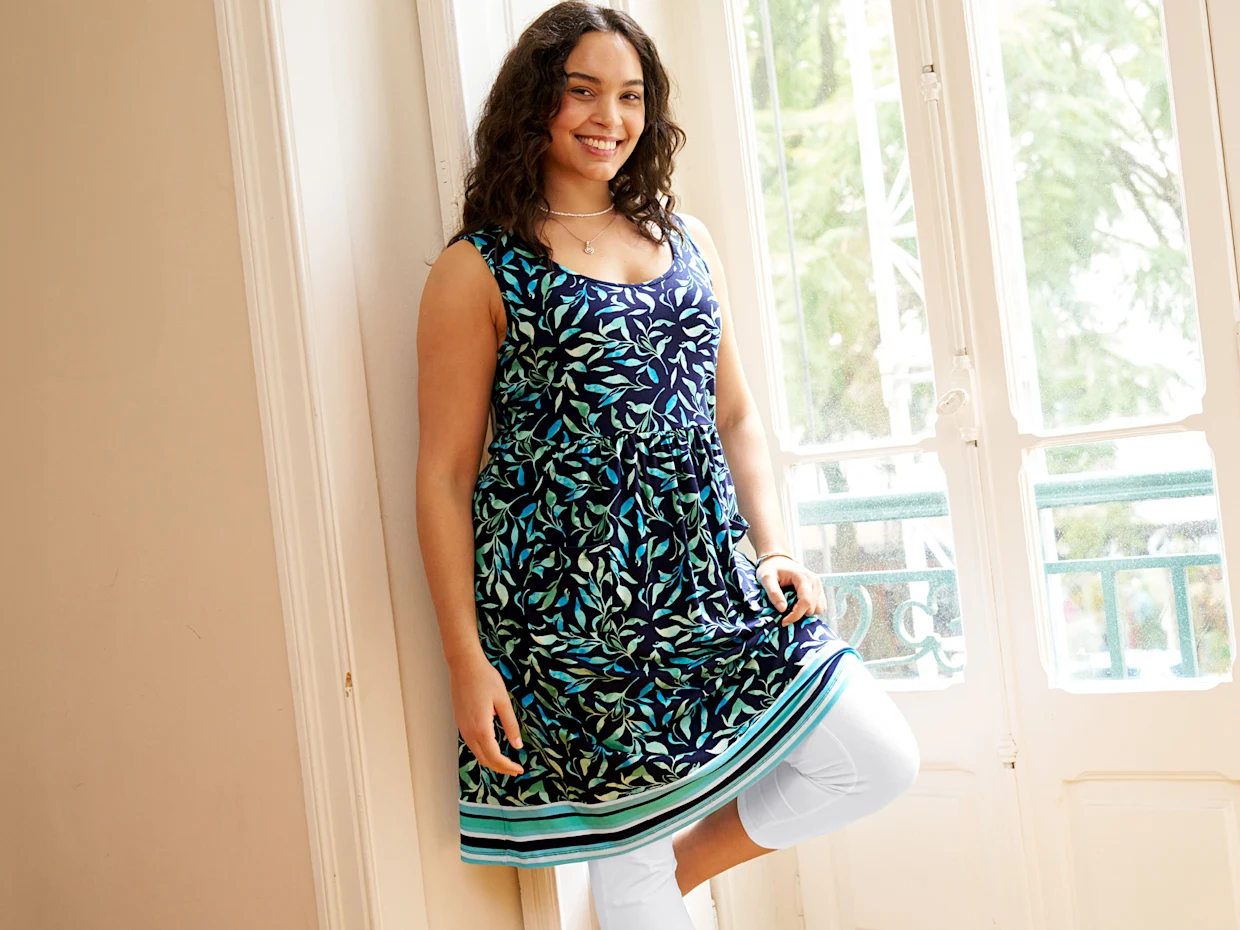 türkis-blau bedrucktes ärmelloses knielanges Kleid mit weißer Capri-Leggings darunter