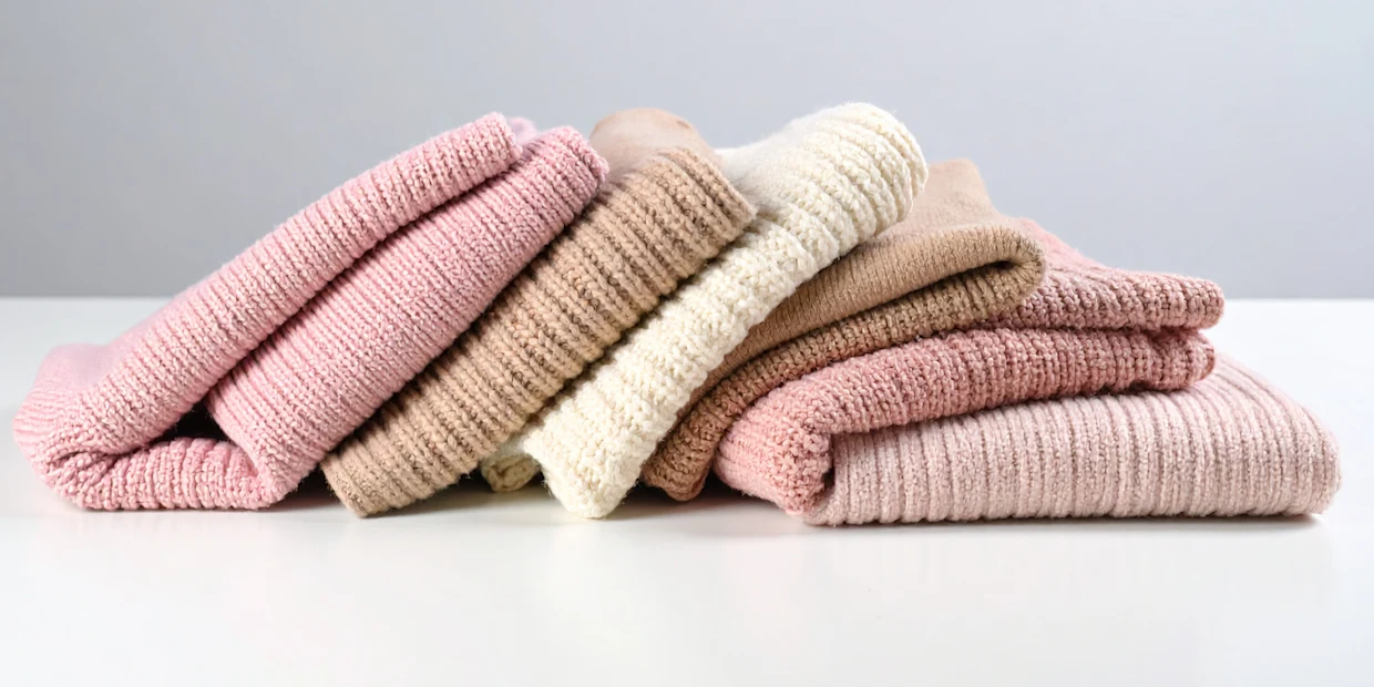Ein Stapelfoto aus pastellfarbigen Strickartikeln Ein Stapelfoto aus pastellfarbigen Strickartikeln