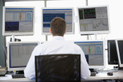 Man looking at stock charts on multiple monitors
