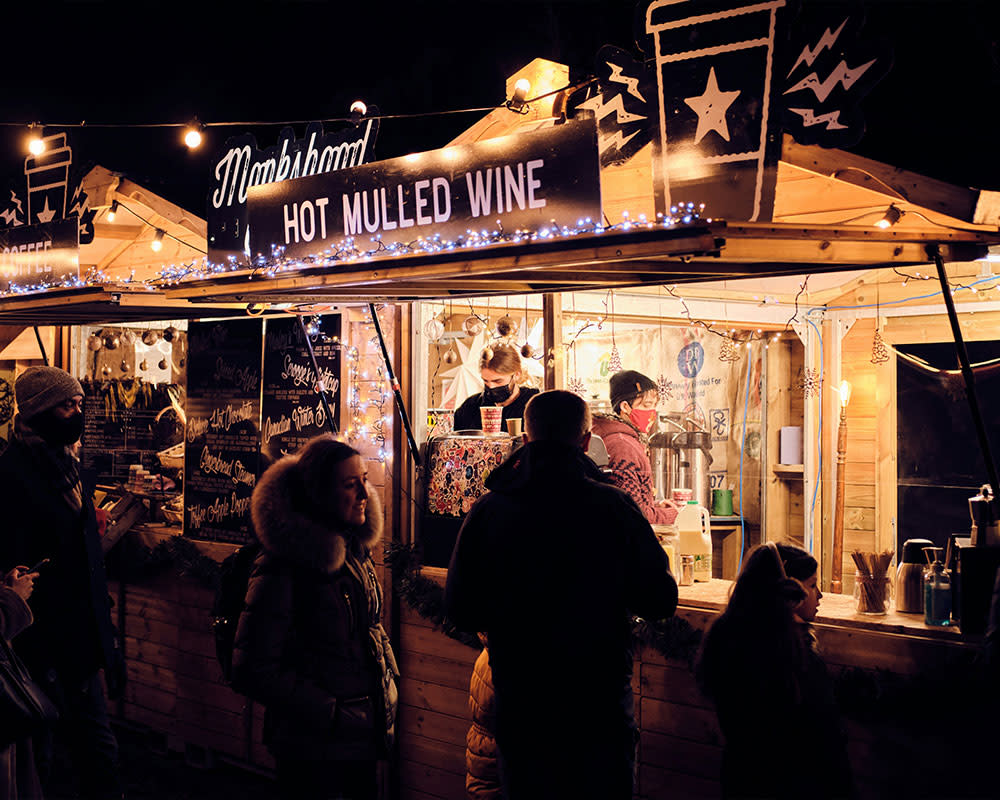 people standing in line at a christmas market for mulled wine