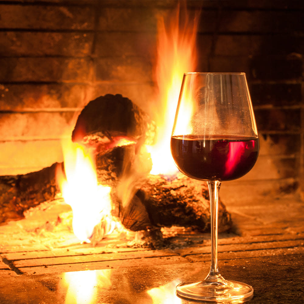 Glass of red wine next to a fireplace