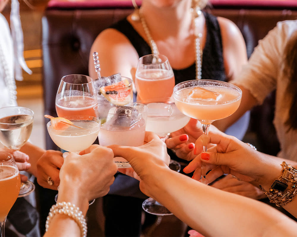 a group cheersing glasses of cocktails and spritz