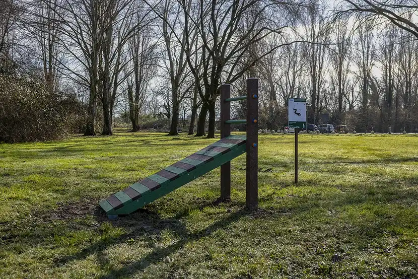 Il parco di trezzano in una giornata di sole, su un ampio prato verde una delle 12 installazioni sportive in plastica riciclata: una panca obliqua e una palina che spiega come utilizzarla.