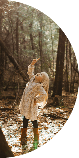 Ragazza nel bosco che punta verso gli alberi