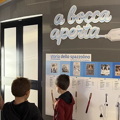 Due bambini guardano la timeline temporale di come si è evoluto lo spazzolino nel tempo.