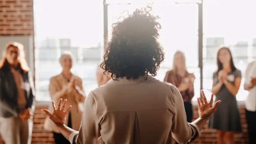 Una donna in piedi di fronte ad altre a rappresentare l’empowerment femminile in un contesto aziendale.