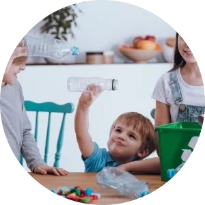 Tre bambini inseriscono delle bottiglie di plastica all’interno di un contenitore per il riciclo.