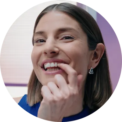 Smiling woman touching her teeth with a finger, displaying a positive dental hygiene routine.