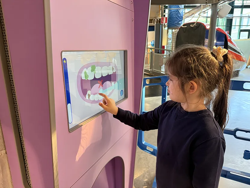 Una bambina durante un gioco interattivo con un tablet alla mostra “A bocca aperta” realizzata da Explora e Oral-B dedicata all’igiene orale.
