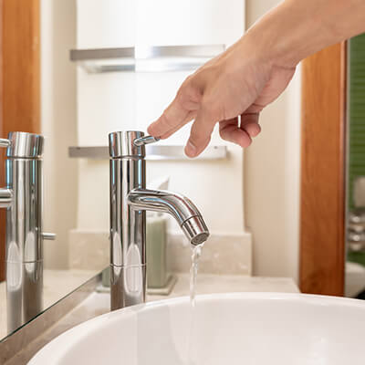 Una persona chiude il rubinetto di casa per risparmiare acqua.