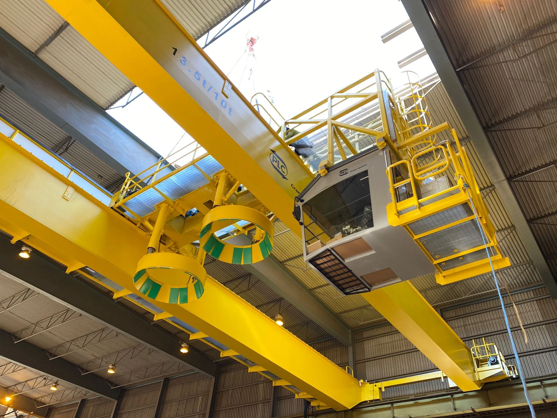 Yellow overhead crane system with maintenance platforms inside an industrial facility