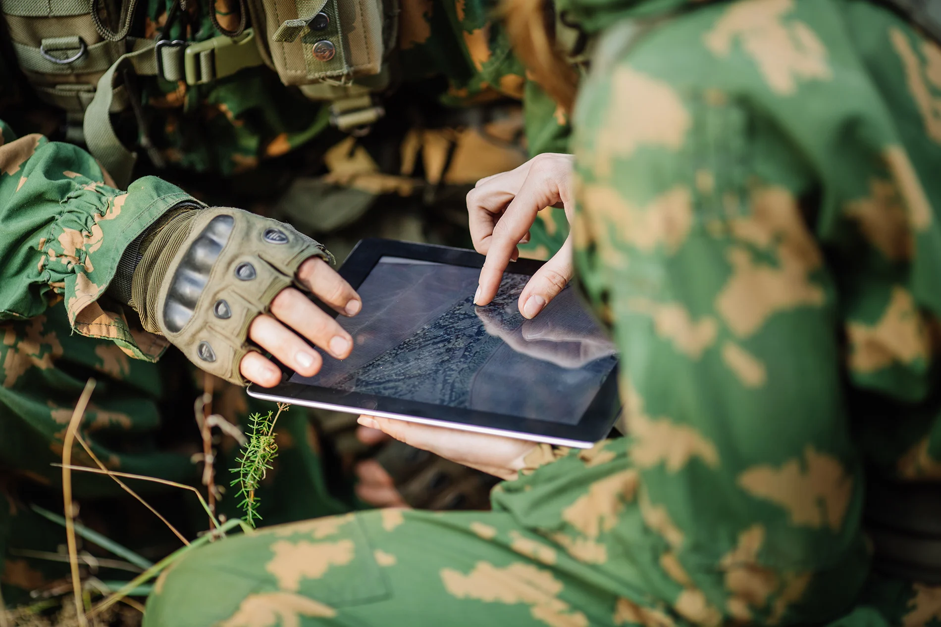 People with camouflage looking at a tablet
