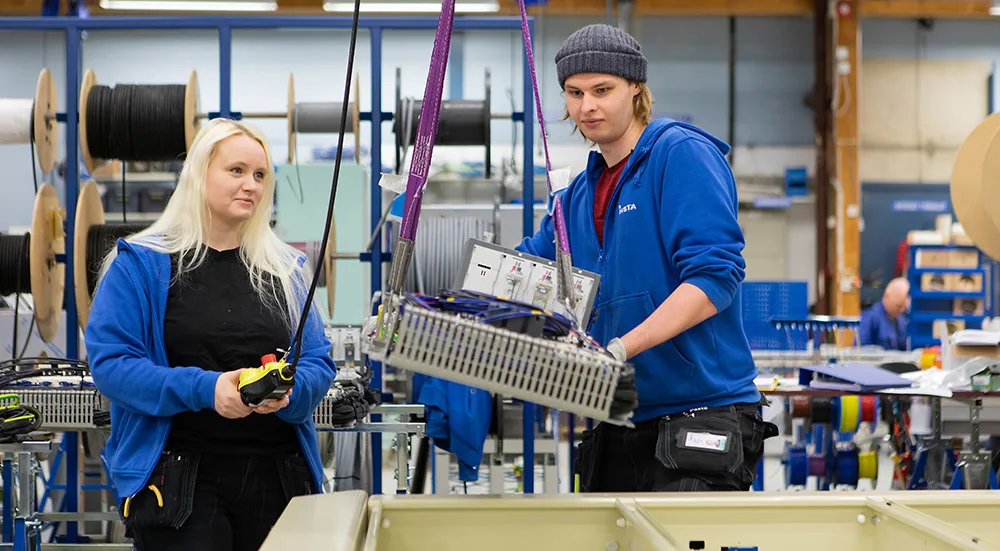 Work carried out in the assembly of industrial electrical and automation cabinets in a production hall, with open cabinets, components and cable reels visible as part of the manufacturing process.