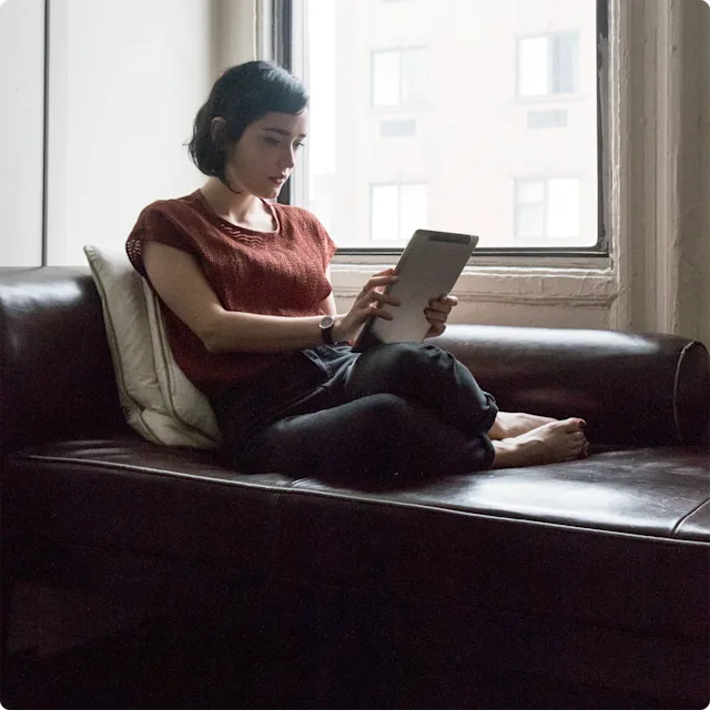 Woman sitting on couch looking at her ipad with futuristic vibe.