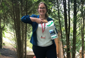 Rose Cashley-Field, Membership and Individual Giving Manager, at Cornwall based, Eden Project holding a CollecTin contactless donation box which uses Give A Little software. She is tapping the donation box with a Cornish pasty!