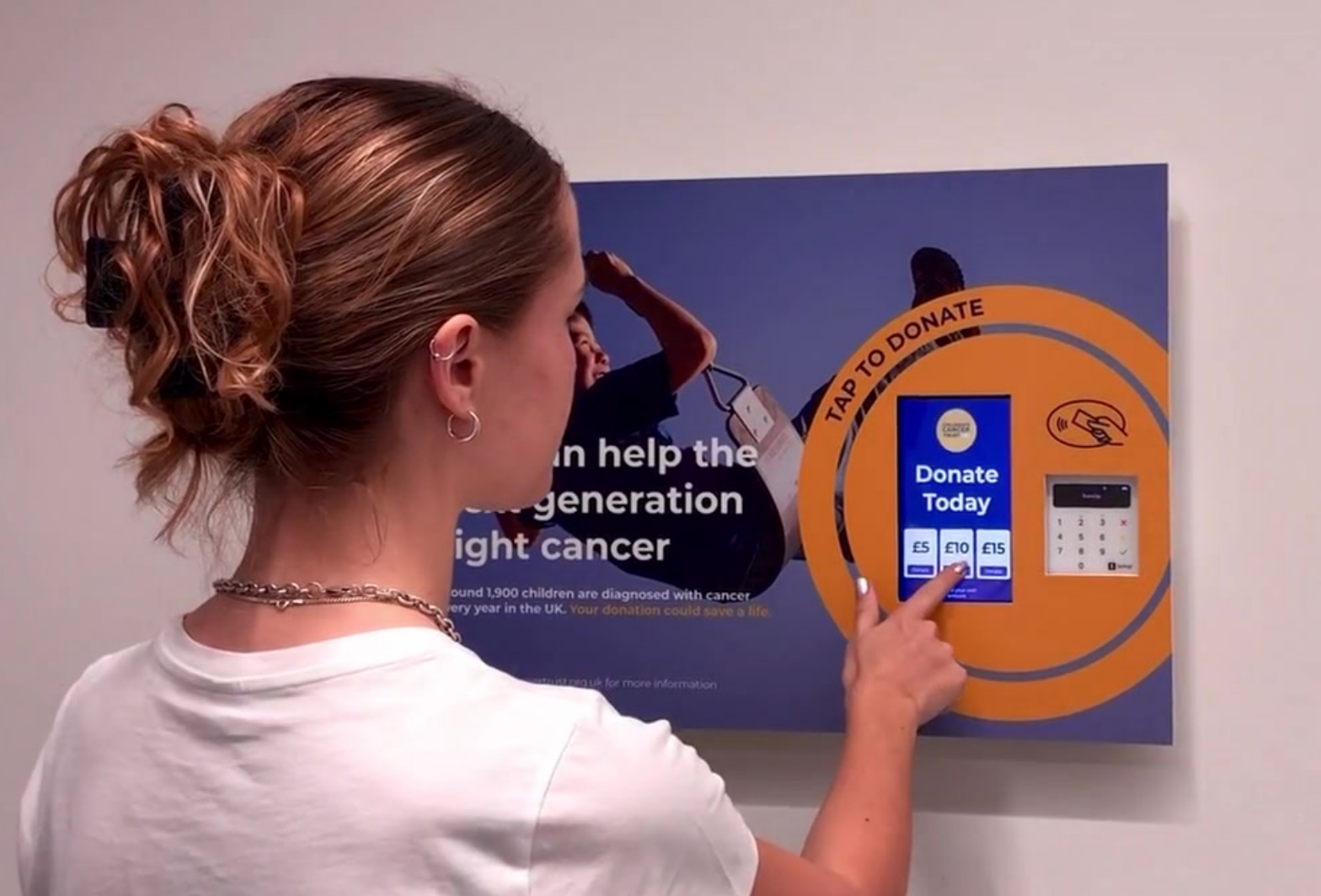 Donor making a donation using a DIY wall mounted point of donation
