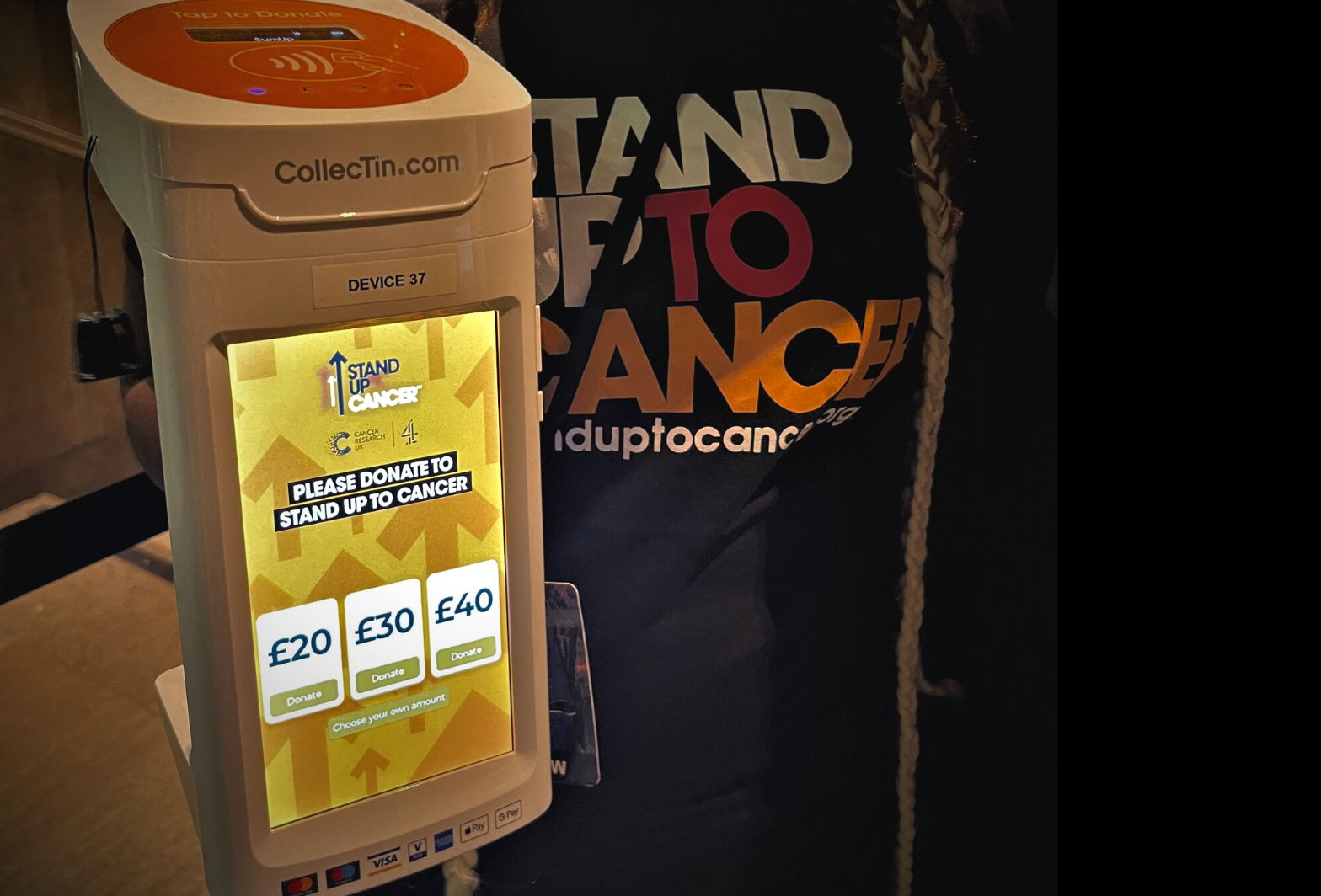 Volunteer holding contactless donation device at Stand Up to Cancer fundraising event