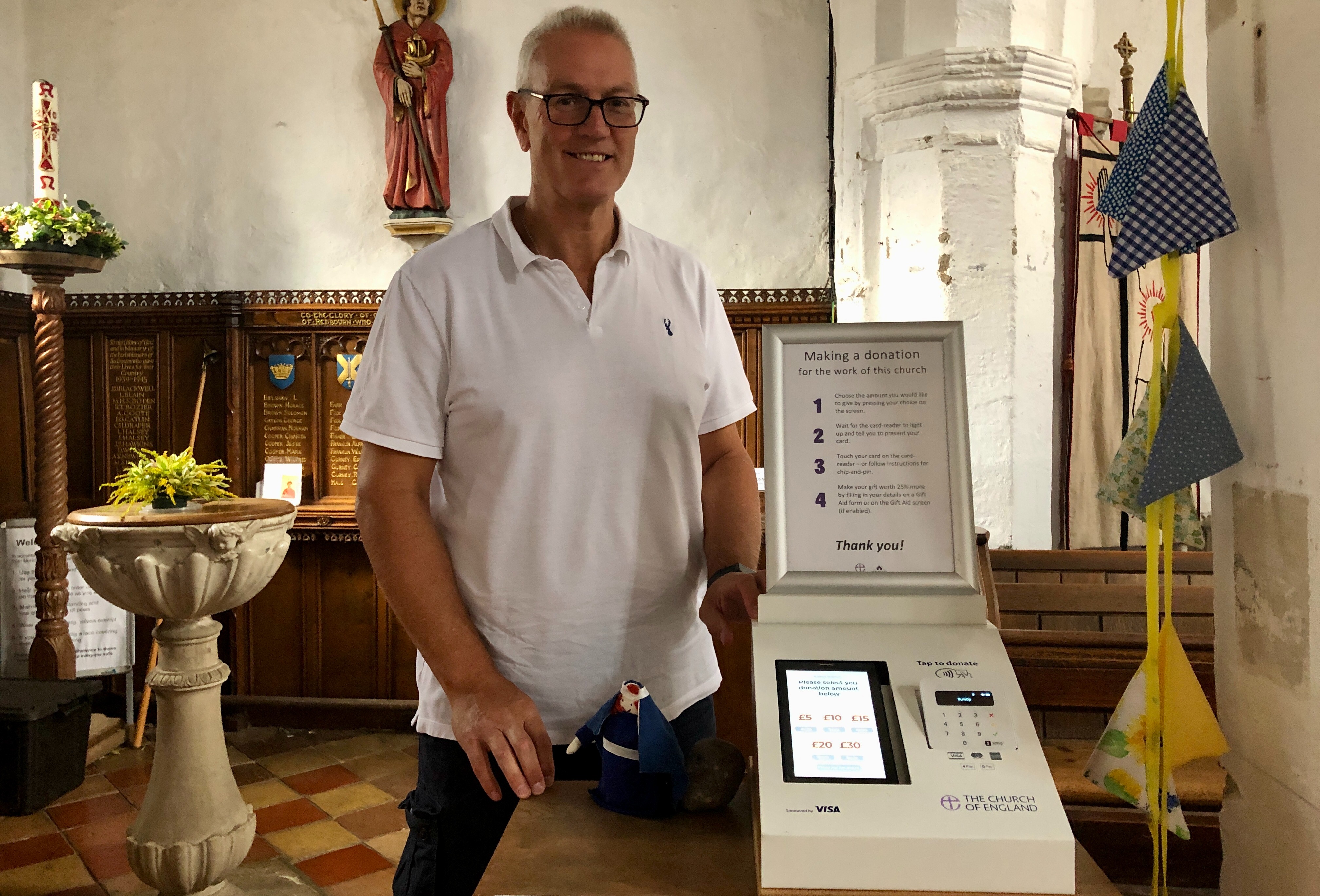Michael, Treasurer at St Marys church in Redbourn is standing next to a donation station installed with Give A Little software