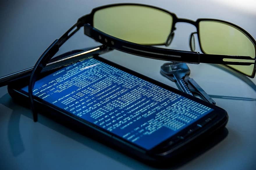 Smartfon z kodem na ekranie, okulary, klucze.
