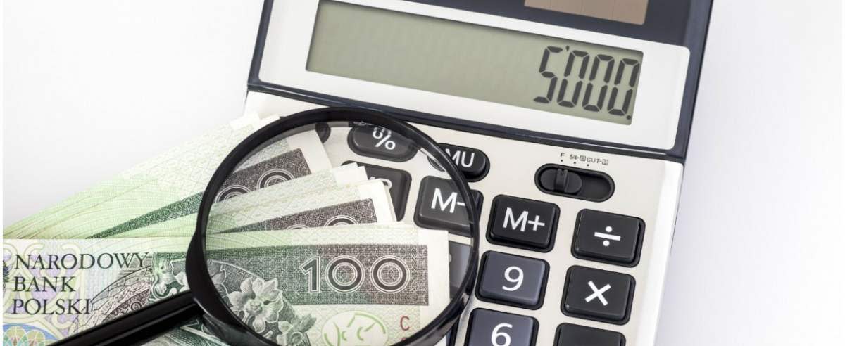 fot: Arkadiusz Ziolek/ East News. n/z Kalkulator z wartoscia 5000 zl, lupa i pieniedzmi na bialym tle.