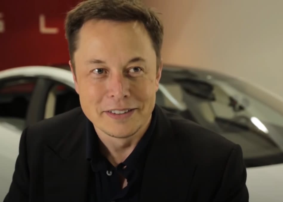 Uśmiechnięty Elon Musk z autem w tle