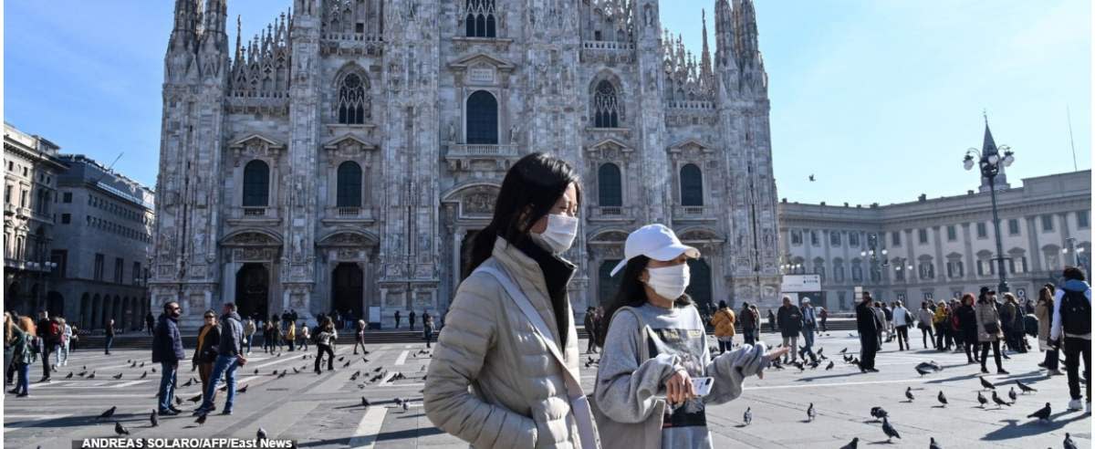 TOPSHOT - Two women wearing a protective facemask walk across the Piazza del Duomo, in front of the Duomo, in central Milan, on February 24, 2020 closed following security measures taken in northern Italy against the COVID-19 the novel coronavirus. - Italy reported on February 24, 2020 its fourth death from the new coronavirus, an 84-year old man in the northern Lombardy region, as the number of people contracting the virus continued to mount. (Photo by ANDREAS SOLARO / AFP)