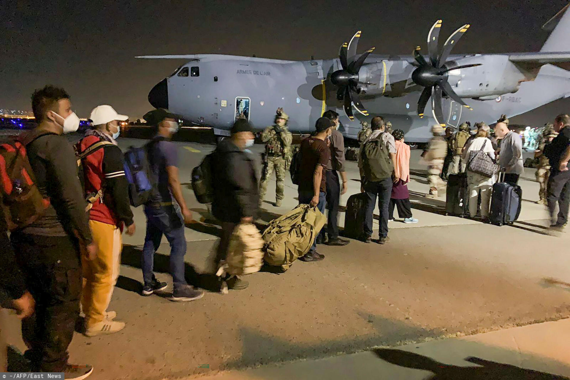French nationals and their Afghan colleagues line up to board a French military transport plane at the Kabul airport on August 17, 2021, for evacuation from Afghanistan after the Taliban's stunning military takeover of the country. (Photo by - / AFP)