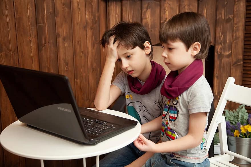 Bliźniaki przed laptopem. Smutne dzieci, bo korzystają z laptopa od Samsunga.