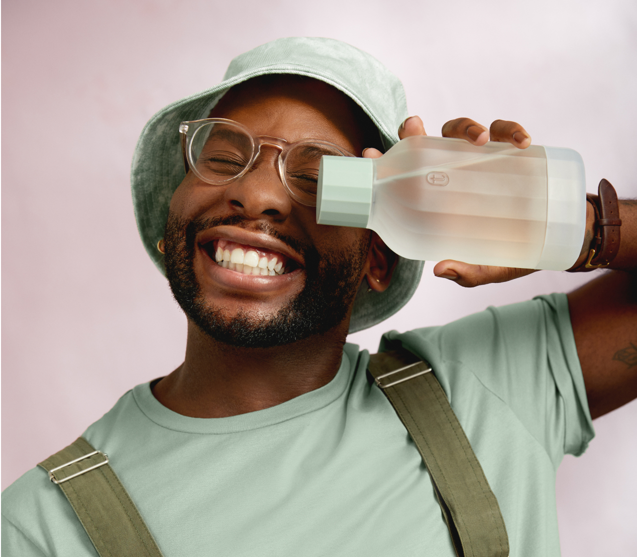 Man in hat smiling and holding Tend Tonic decanter