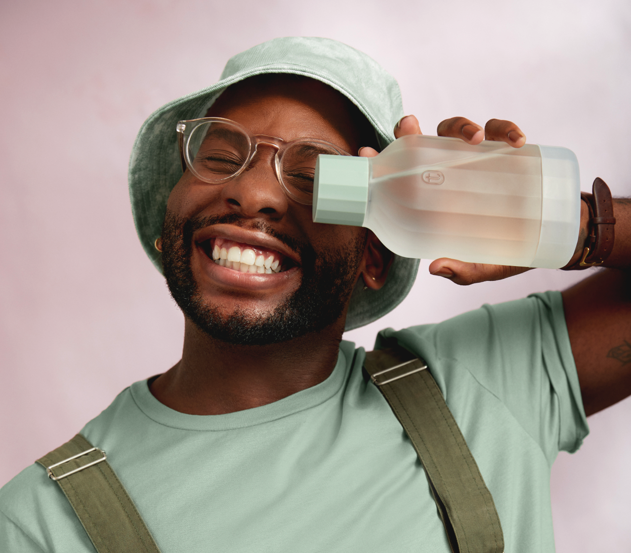 Man in hat holding Tonic decanter sideways and smiling