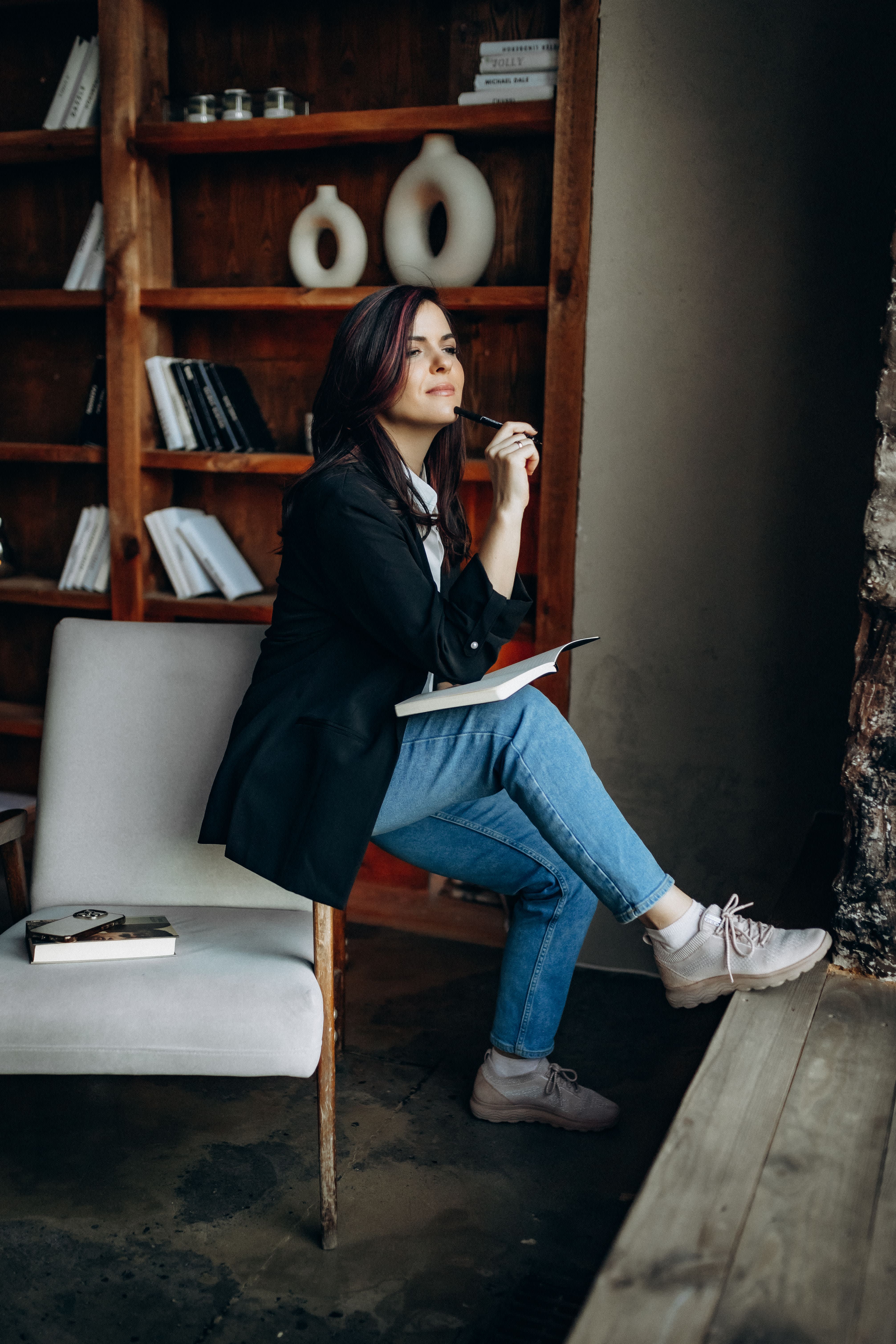 The author sits in the chair and looks to the window in contemplating posture.