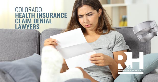 A frustrated woman looks at a letter informing her that her health insurance claim has been denied