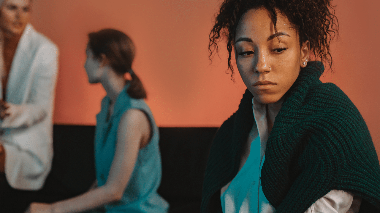 a black woman in the foreground while her white coworkers talk in the background
