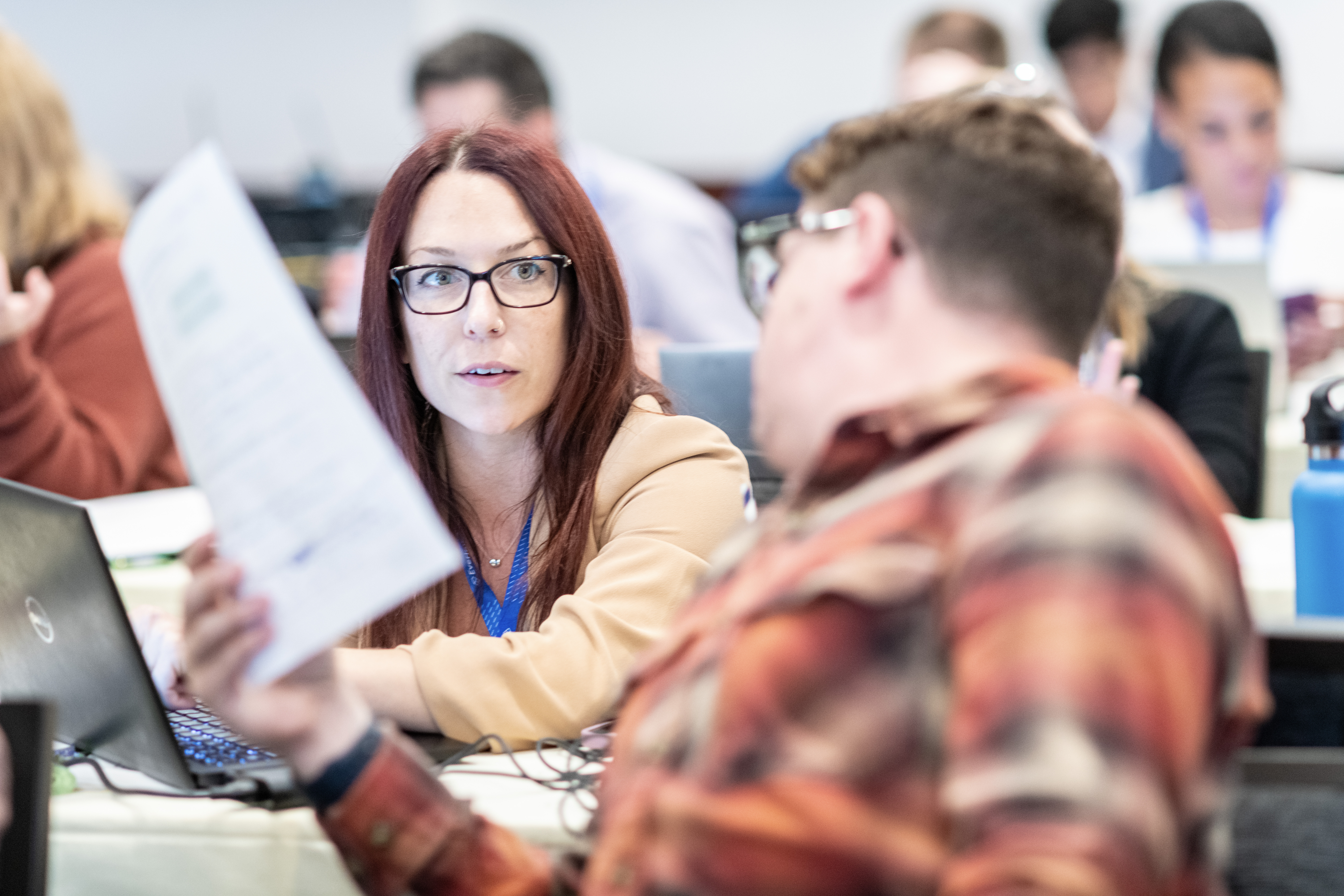 Two Everlaw Summit attendees exchange papers and advice during a user education session. 