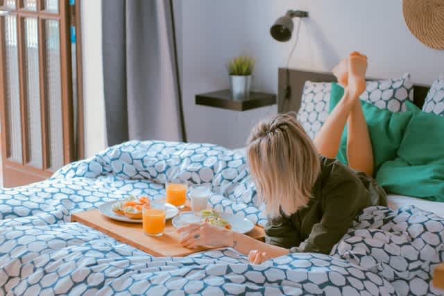 Woman on bed eating breakfast