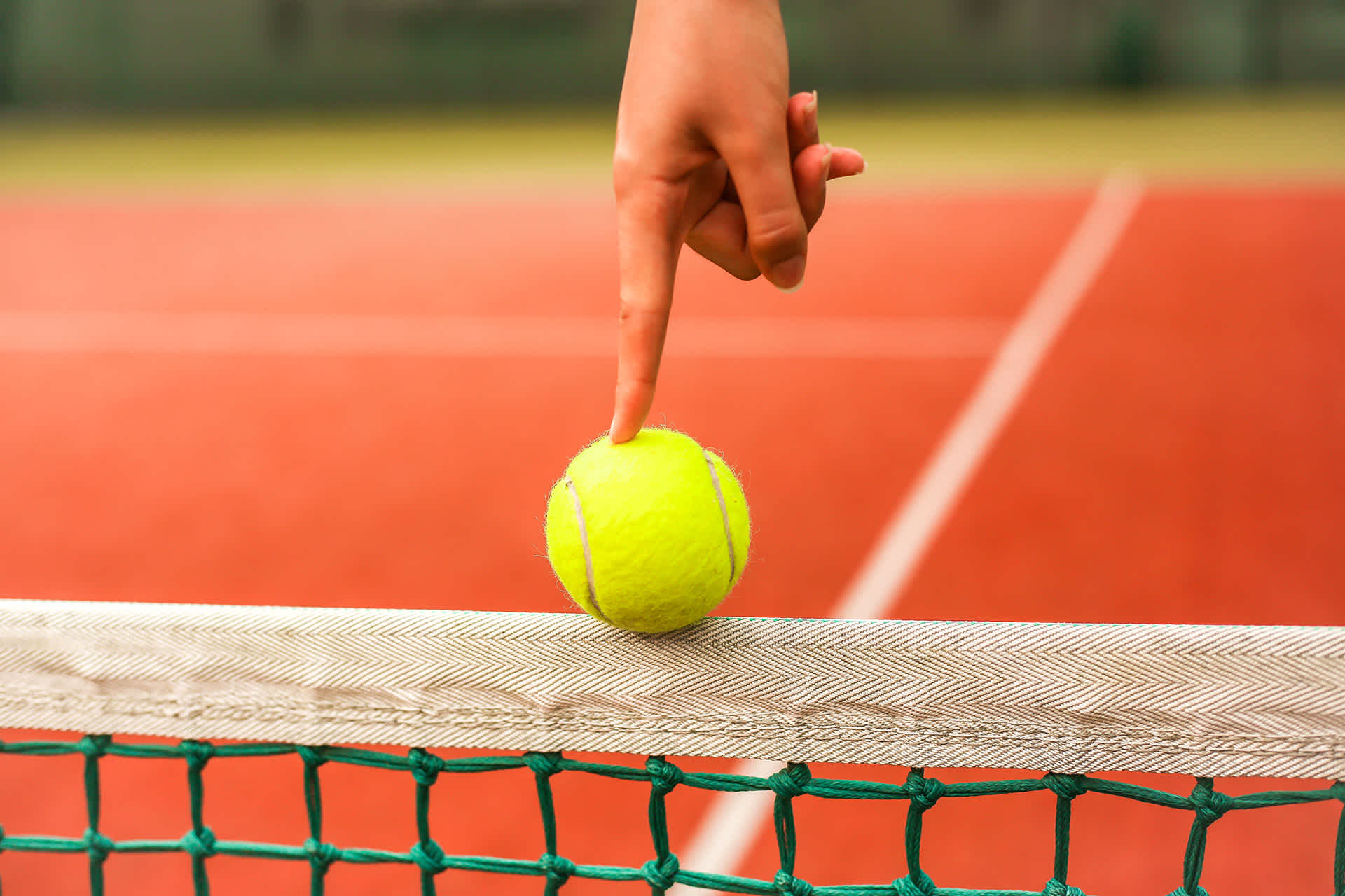 Tennis ball being balanced on a tennis net