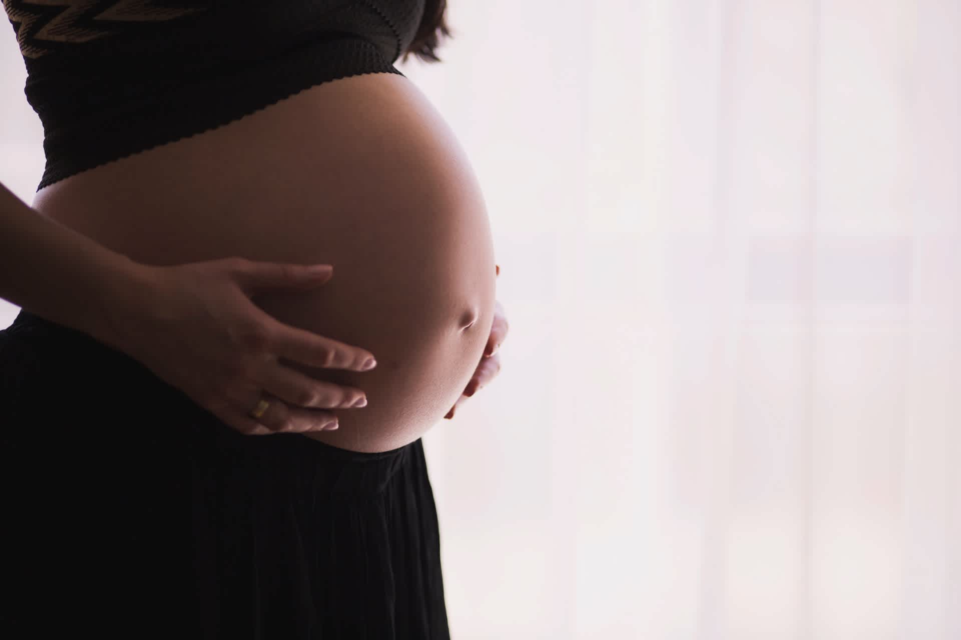Image of a woman holding her pregnant belly