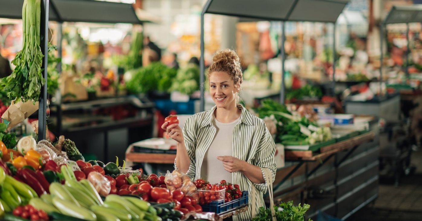 happy-woman-at-marketplace-with-tomato-in-hand-smi-2025-03-30-22-02-04-utc