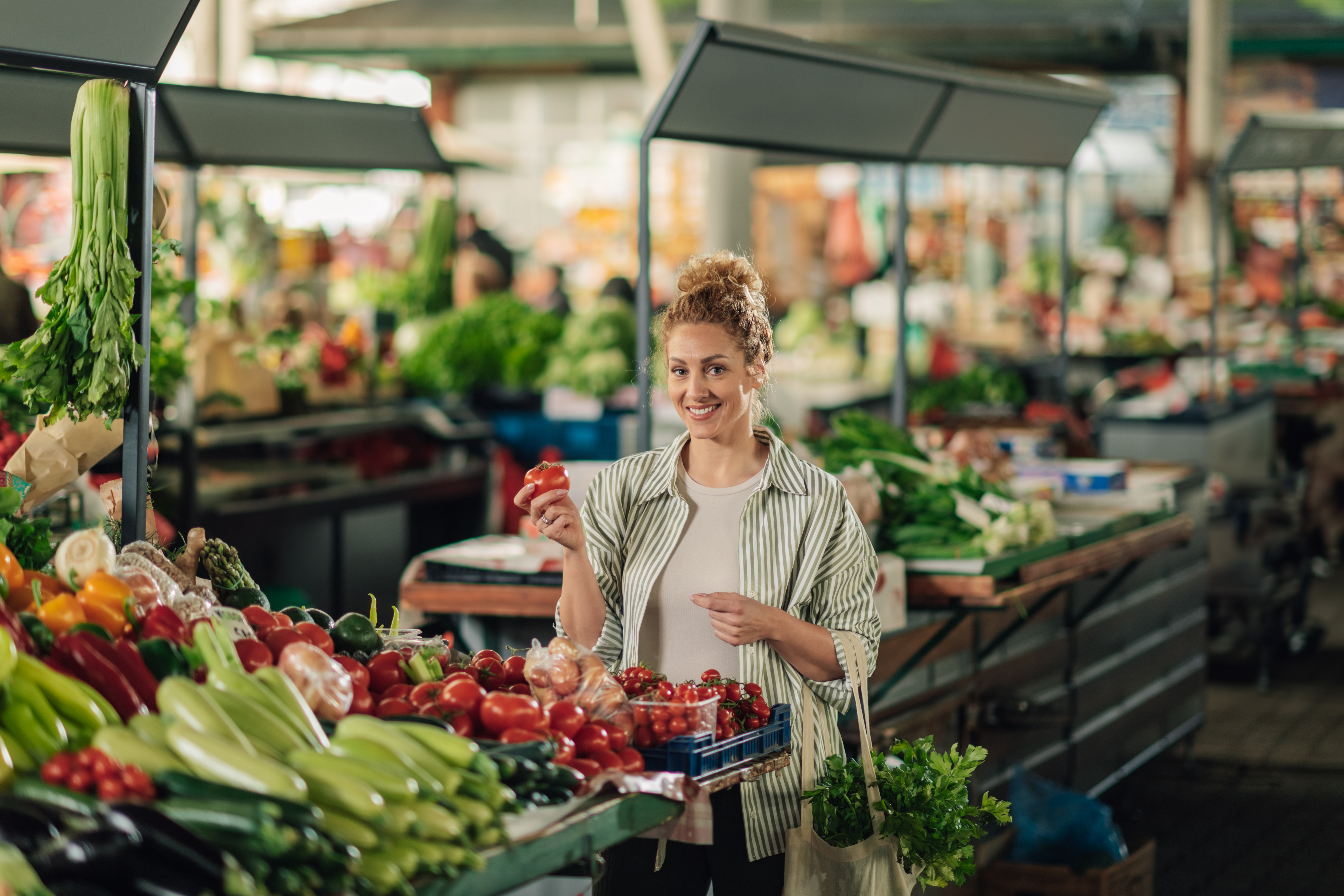 happy-woman-at-marketplace-with-tomato-in-hand-smi-2025-03-30-22-02-04-utc