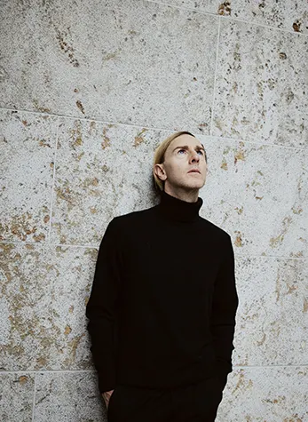 Richie Hawtin, pioneiro da música eletrônica, apoiando-se em uma parede