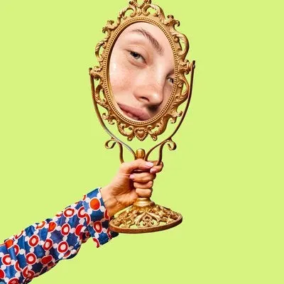 Woman holding a small, old-fashioned mirror.