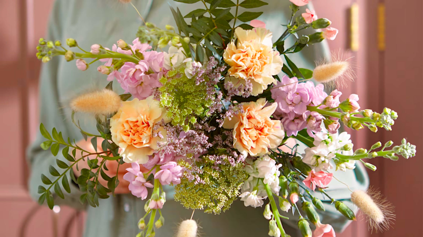 A bunch of pink and peach colored flowers with green leaves