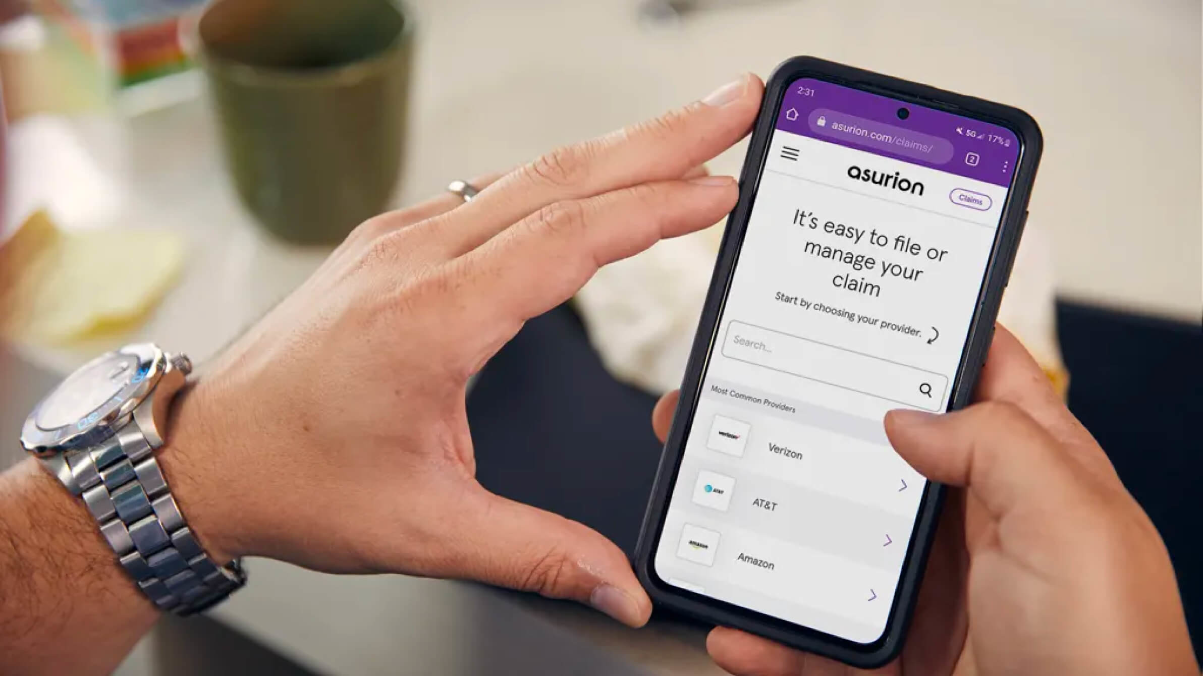 Mobile phone in a man's hands, showing the Asurion website on the screen