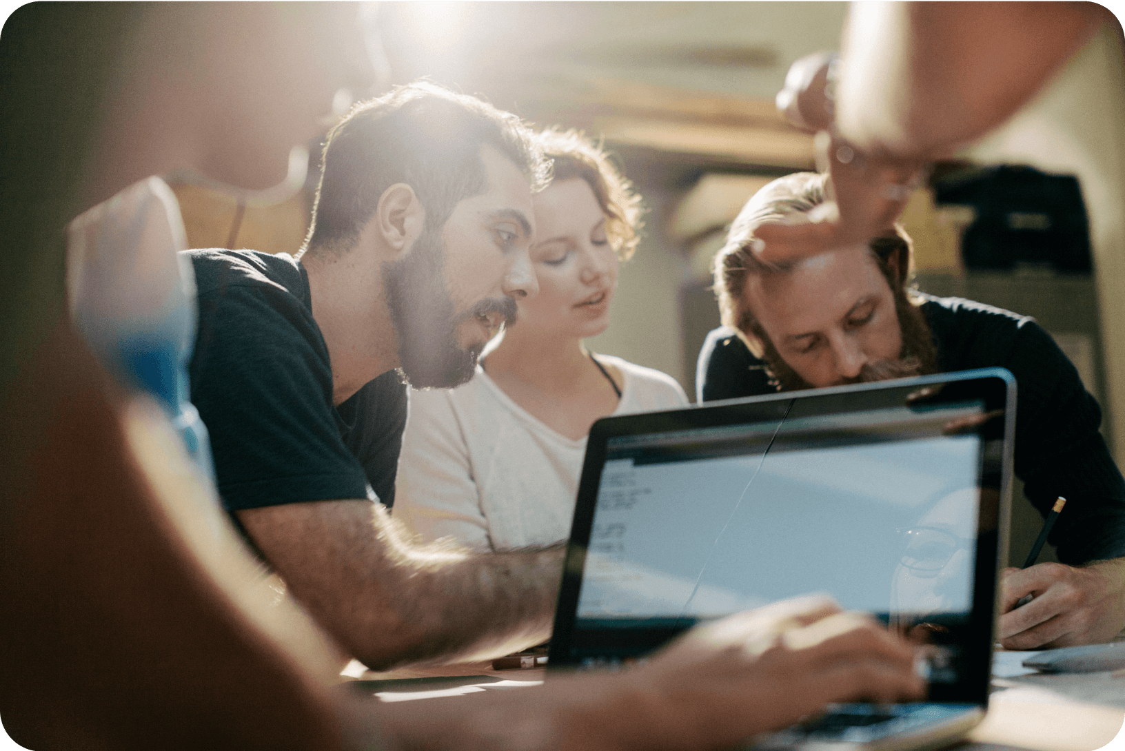 A group of colleagues collaborate around a laptop