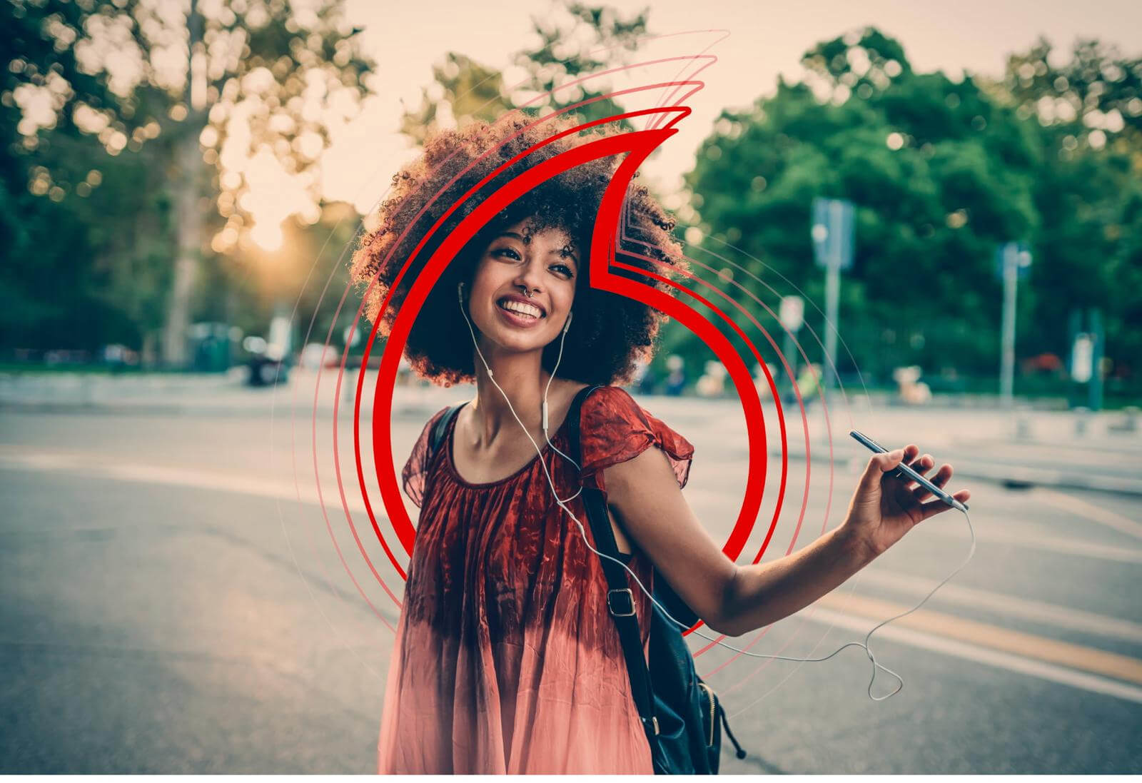 Female with headphones in her ears, holding her phone as she walks down the street.