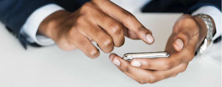 Hands operating a mobile phone.