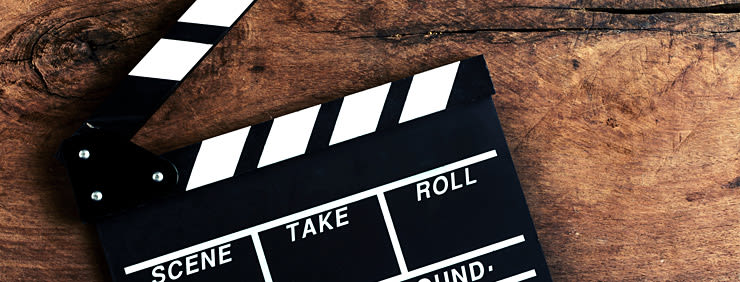 A black and white film clapperboard resting on a rustic wooden surface.
