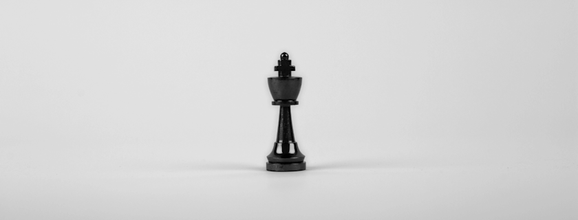 A single black king chess piece centered on a light grey background.
