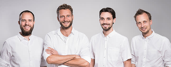 Four smiling men wearing white shirts standing together.